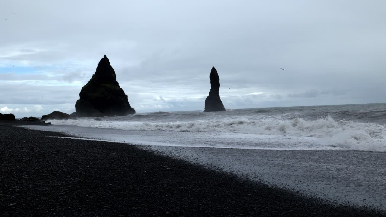 disparo manual al nivel del suelo de una playa negra en islandia, con las olas de agua acercándose