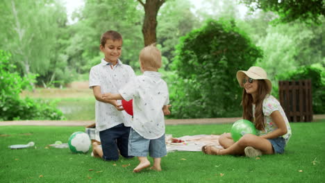 joyful kids playing with balls in park. three kids having fun in summer park