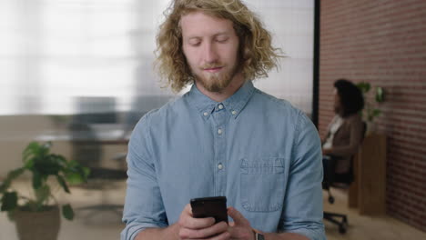 portrait of young charming blonde man  texting browsing using smartphone social media app checking messages in office workspace