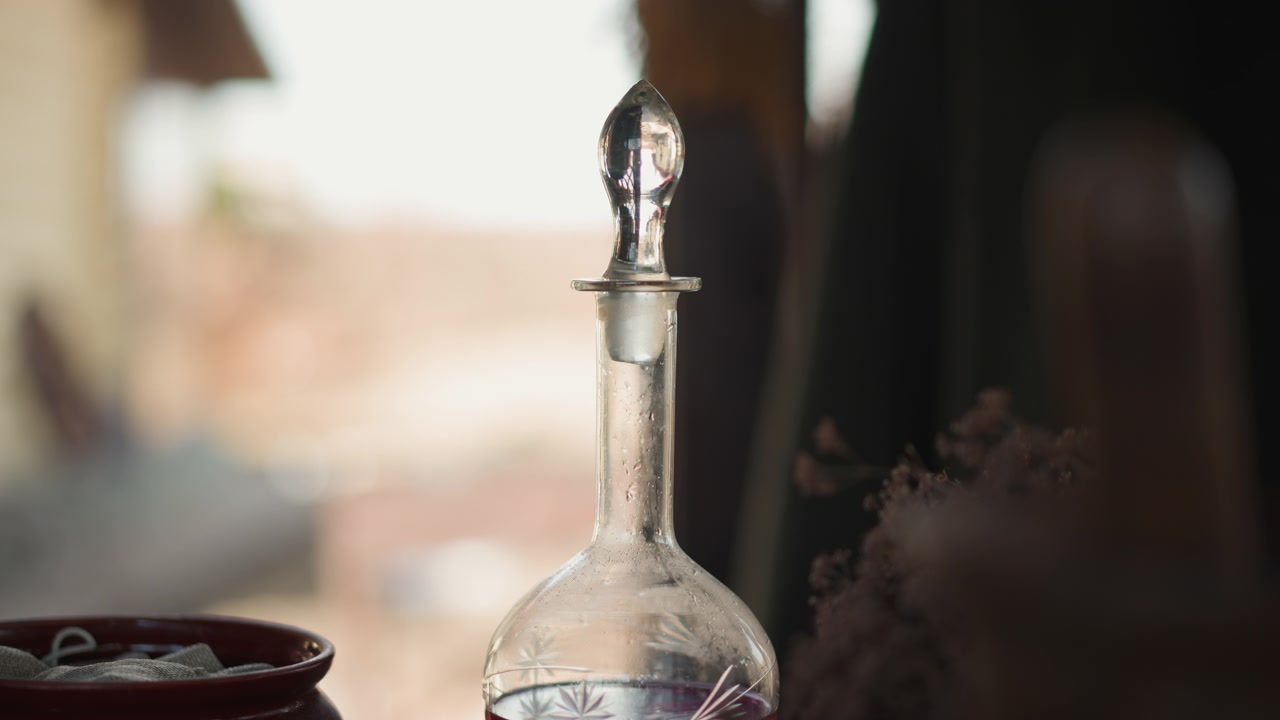 Clear glass decanter with round stopper stands on interior table, glowing in warm backlight with soft reflections, shallow depth of field, elegant curves, quiet natural window light and calm mood