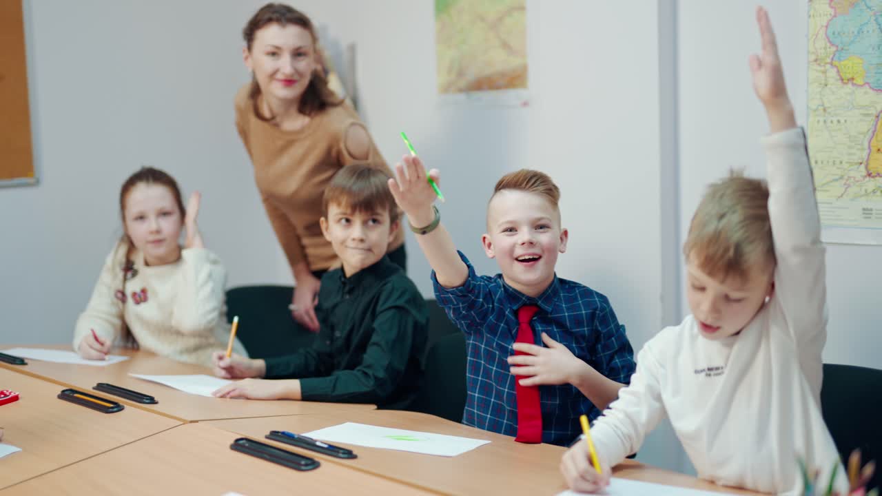 Children study at primary school. All kids rise hands up to answer during the lesson in the classroom. Elementary education concept.