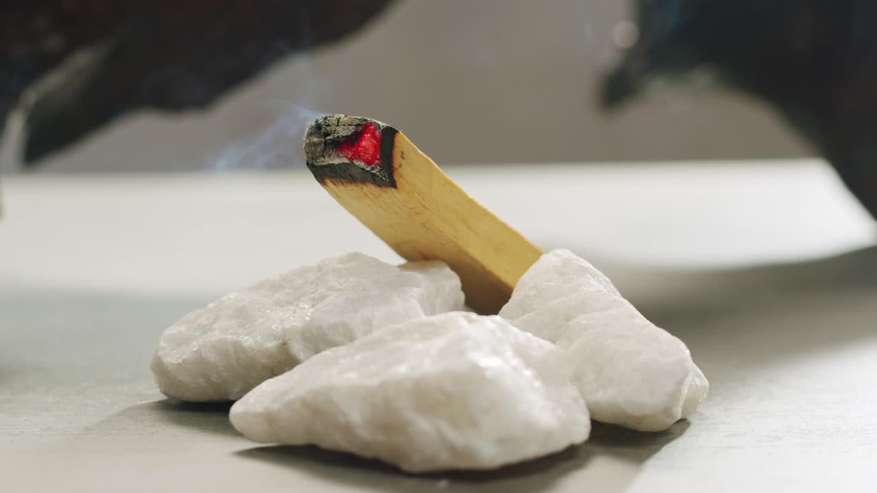 Person holding Palo Santo wood stick in hand, aromatic Palo Santo burning on black background, smoke spreading around, slow motion video clip, high quality 4k close up footage. High quality 4k footage