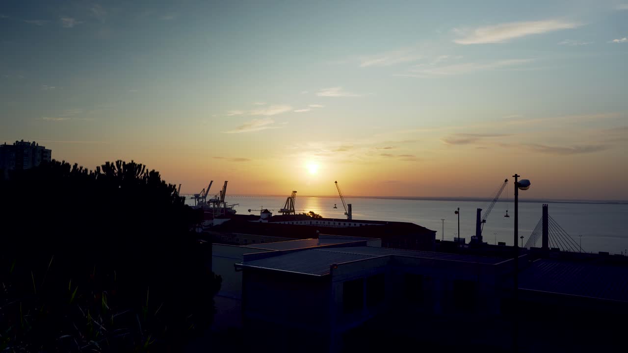 녹슨 울타리를 통해 크레인 실루엣으로 리스본 항구 일출