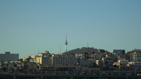 cityscape of namsun n seoul tower and yongsan-gu district at bright day seoul, south korea. traffic on gangbyeon expressway with namsan mt. on clear blue cloudless sky background