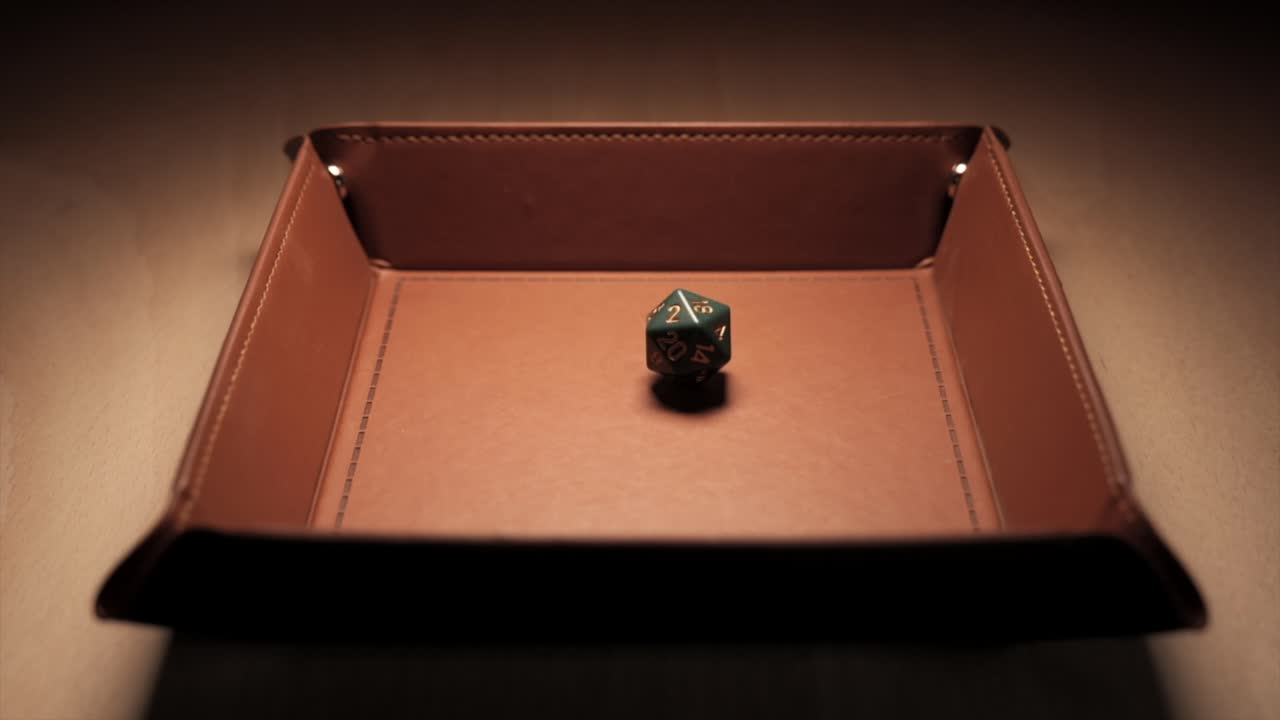 un dado de 20 caras cayendo en una bandeja de dados en cámara lenta