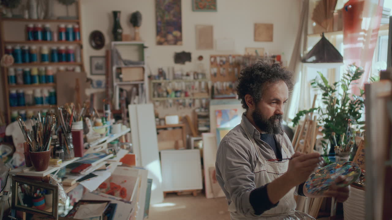 Artist Painting on Canvas in Spacious Studio Filled with Art Supplies
