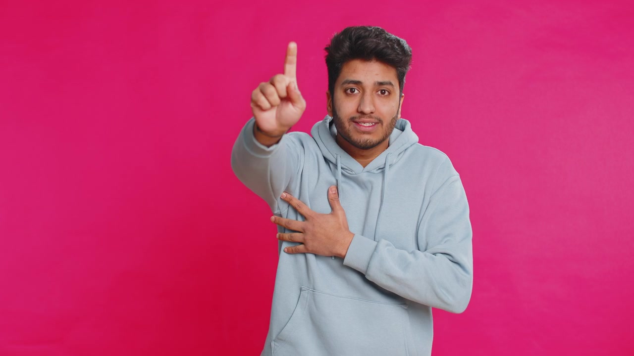 Indian young man shouting calling out loud holding hands near mouth yelling waving excited indoors