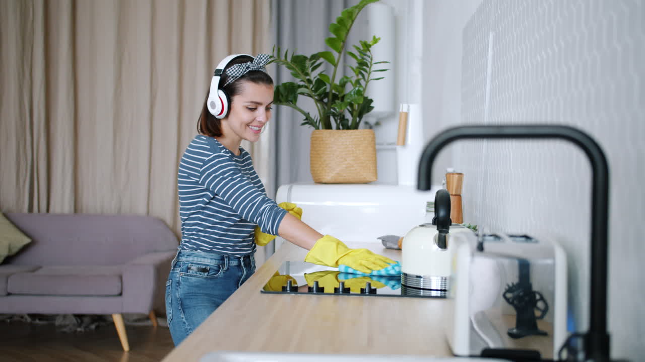Woman Cleaning Kitchen While Listening to Music