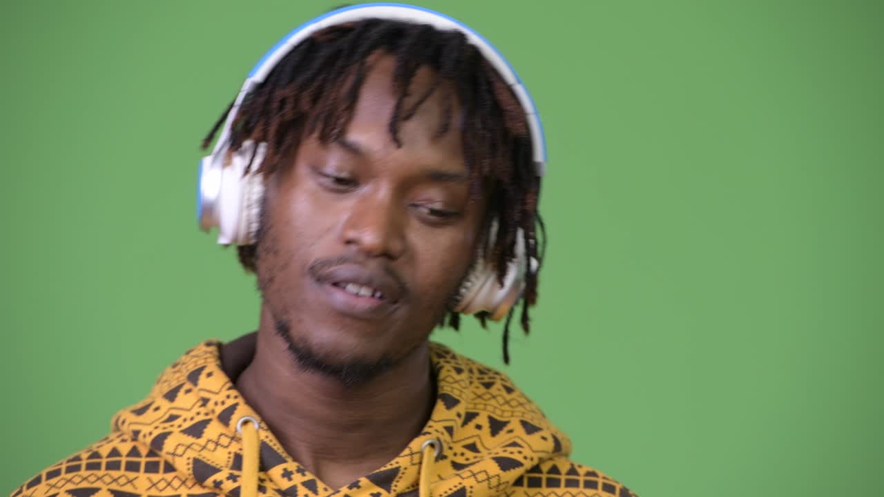Giovane, bello e felice uomo africano che sorride ascoltando musica