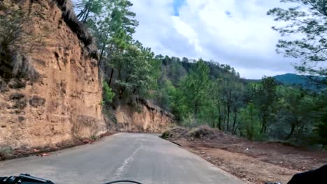 Two-bicyclists-ride-their-bicycle-on-a-road-inside-of-a-forest,-hill,-and-village-in-Guatemala,-North-America