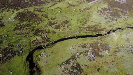 winding river of dark water at base of hillside landscape in sierra segundera spain