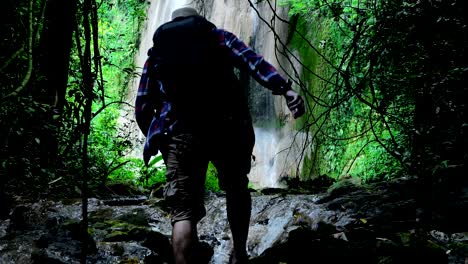 adventurers asian men. traveling in the forest and new discovery waterfalls with sunlight. travel lifestyle and success concept vacations into the wild wearing cozy shirt,hat with backpack.