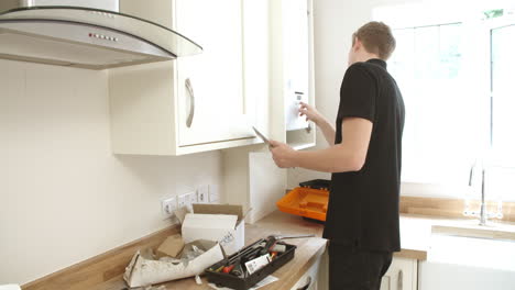 Young-technician-servicing-boiler,-using-tablet-computer