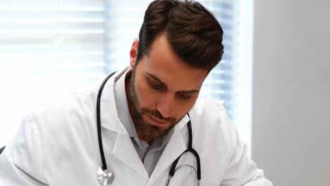 médico masculino escribiendo en el clipboard en el escritorio