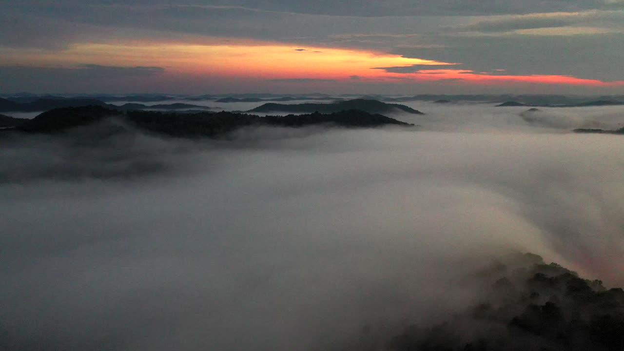 황혼 무렵 낮은 안개 구름 위로 날아가는 드론 샷