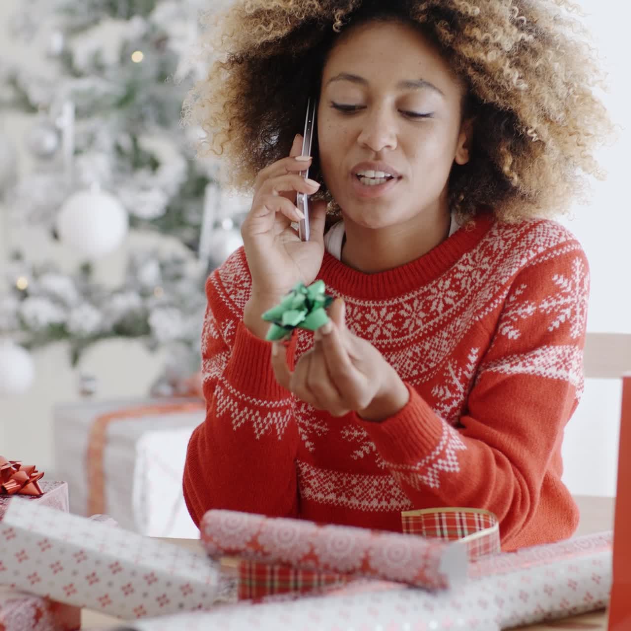 mujer hablando por celular mientras envuelve regalos
