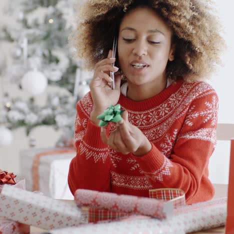 Woman-chatting-on-a-mobile-as-she-wraps-gifts