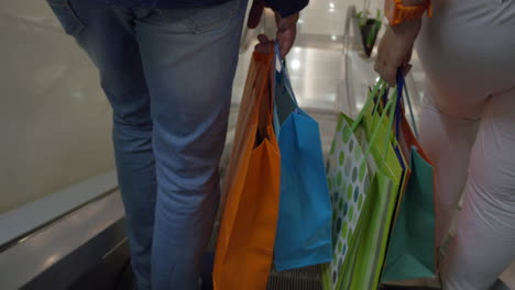 couple with shopping bags riding escalator