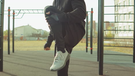 man stretching legs on workout playground