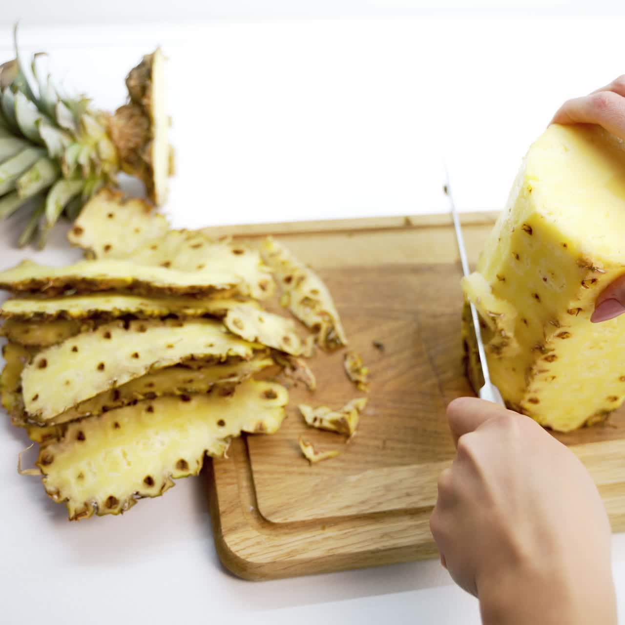 Hands slicing pineapple