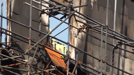 a firefighter is seen directing operations at a window as others dowses down a tower block covered in flammable cladding that was totally destroyed by a fire.