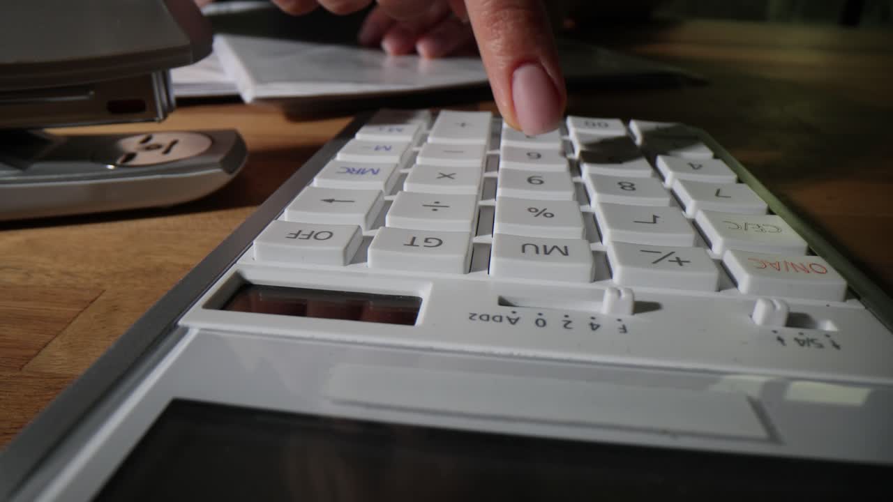 Close-up of a hand using a calculator on a desk