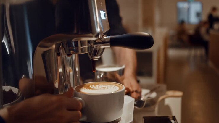 Barista prepares a latte with beautiful latte art using an espresso machine in a cafe