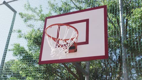 flying ball on sunny basketball court, in slow motion