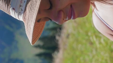 Macro-shot-showing-pretty-face-of-girl-smelling-flower-outdoors-on-meadow-during-summer-day