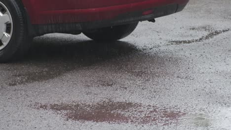 raining puddle with red car reflection on a car park