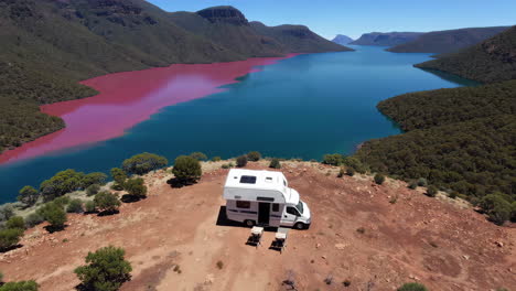 campervan parked on a hill overlooking a striking bi-colored lake and mountains