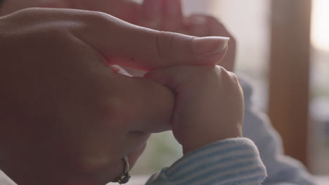 close-up-mother-holding-baby-hands-playfully-kissing-fingers-nurturing-newborn-caring-for-infant-at-home-enjoying-motherhood
