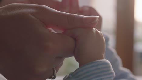 close up mother holding baby hands playfully kissing fingers nurturing newborn caring for infant at home enjoying motherhood