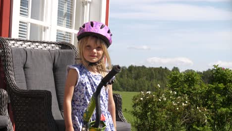 young blonde girl wearing helmet smiles outdoors, slow motion shot