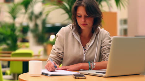 estudiante sonriente estudiando en la cantina con una computadora portátil