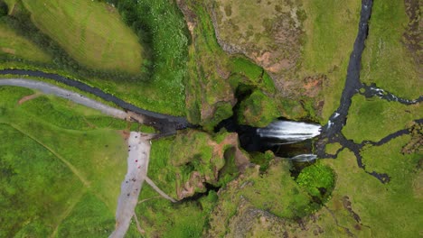 exuberante cascada de gljufrabui verde con agua en cascada, pan aérea de arriba hacia abajo