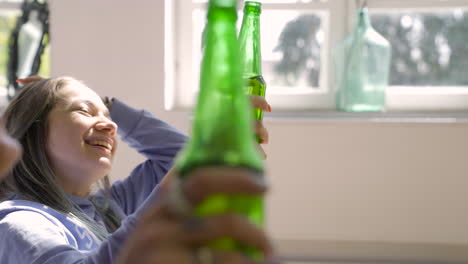 close up of a young girl laughing and drinking beer with friends at home