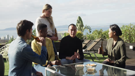 group of friends drinking a beer and discussing on a rooftop