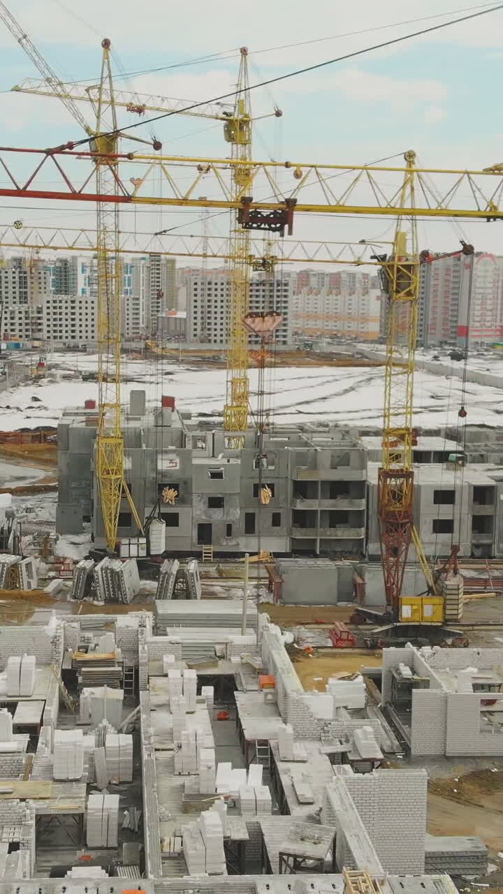 motion above construction site with tremendous yellow cranes against residential houses district on weekend areal view