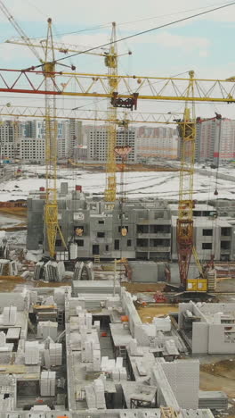 motion above construction site with tremendous yellow cranes against residential houses district on weekend areal view
