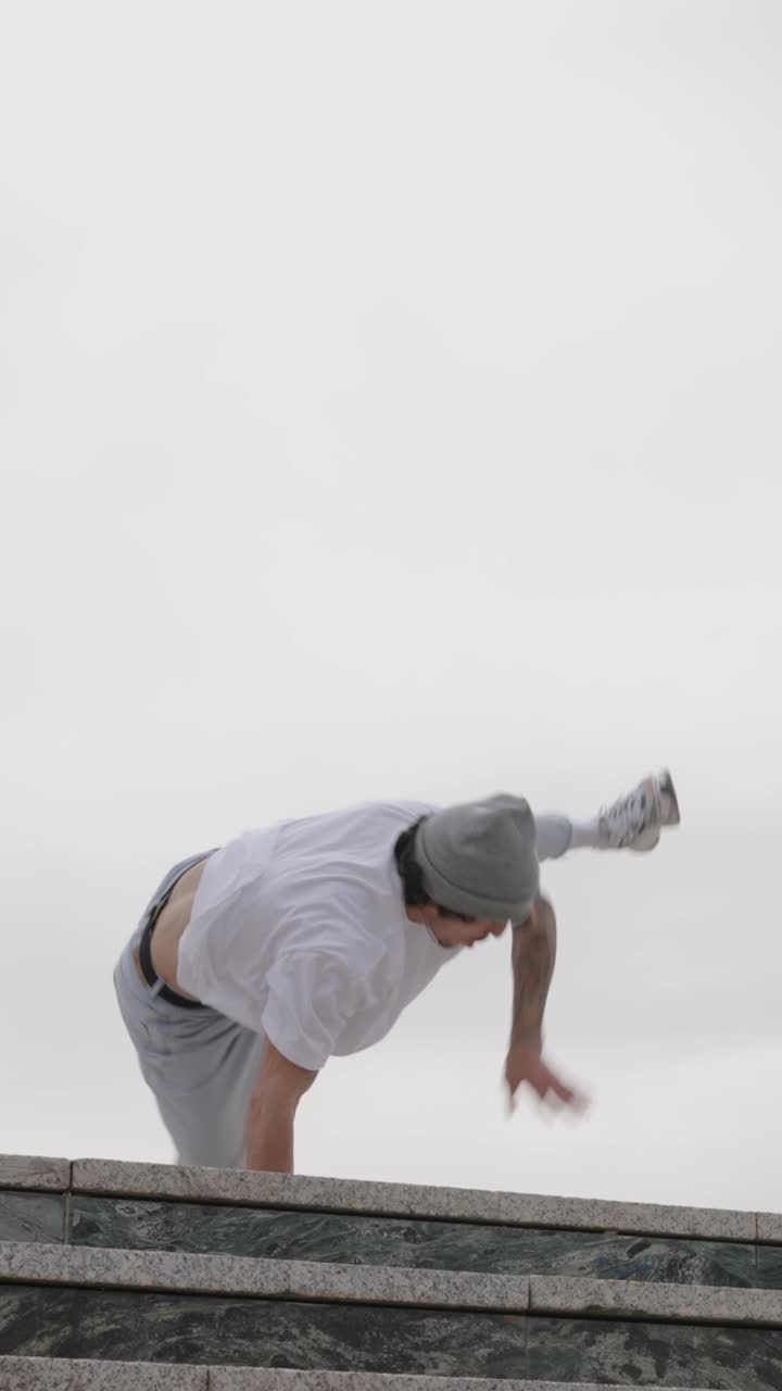 Breakdancer performing acrobatics on building ledge