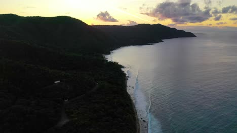 golden hour drone shot reveals a peaceful glowing sky over the virgin islands, casting soft light on rolling waves and long shadows across a scenic peninsula in st. croix
