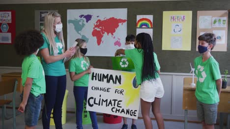 grupo de niños con una pancarta de cambio climático y un contenedor de reciclaje en la escuela