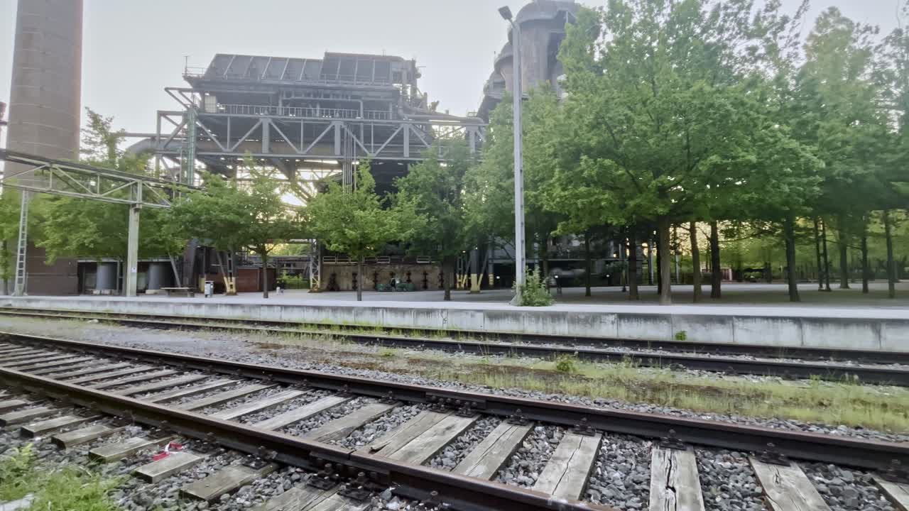 железнодорожная станция в современном дизайне заброшенная промышленная зона для производства стали с деревьями дорожками и стальными конструкциями вечером в ландшафтных парках в северном дюсбурге в германии