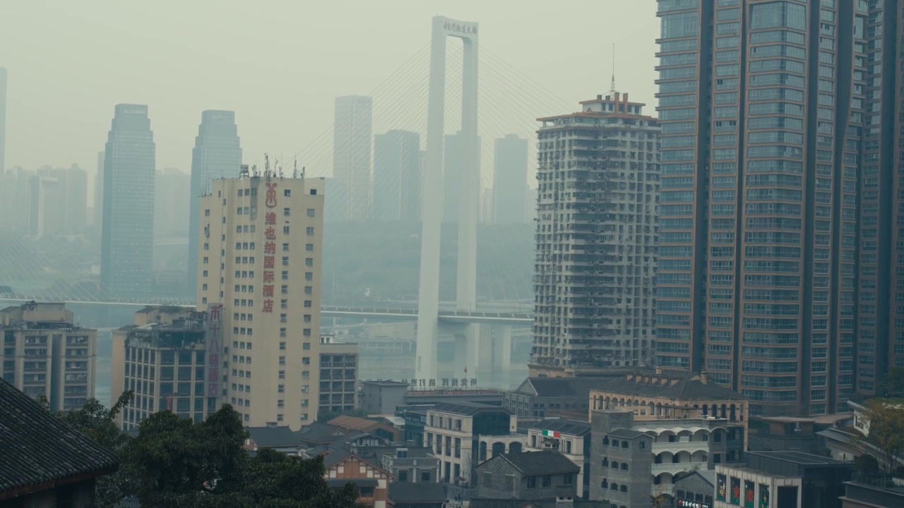 Horizonte urbano denso de Chongqing com ponte estaiada e o Rio Yangtze sob névoa intensa durante o dia.