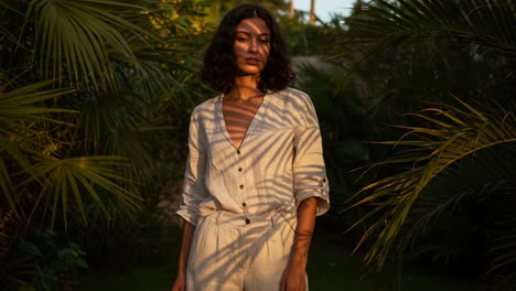 a stunning portrait of a woman surrounded by lush tropical foliage, captured in the soft glow of sunset light radiating through shadows and greenery