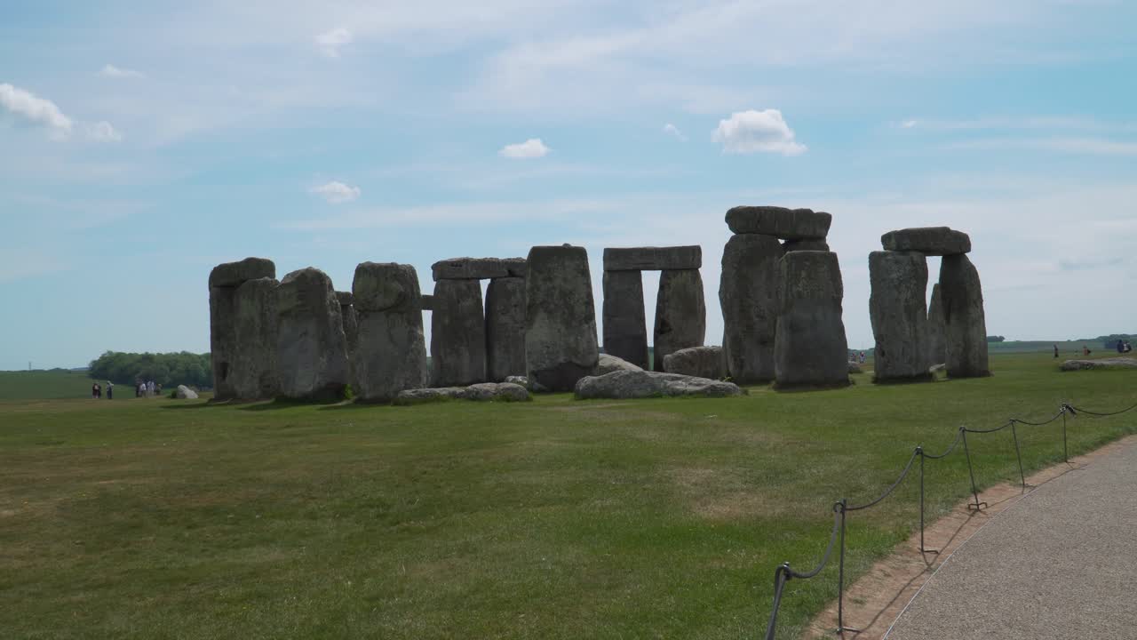 Close up view to the Stonehenge a prehistoric megalithic structure on Salisbury plain in Wiltshire England. Steady camera, people moving around, blue sky with some clouds on a sunny day.