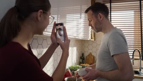 caucasian teenager girl recording her father during the cooking