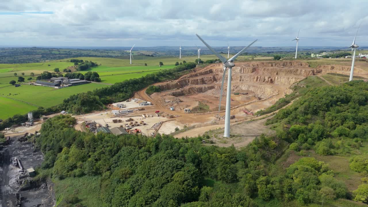 Aerial drone shot showing renewable energy turbines, quarry site, and Carsington countryside with blue lake and farmland in England