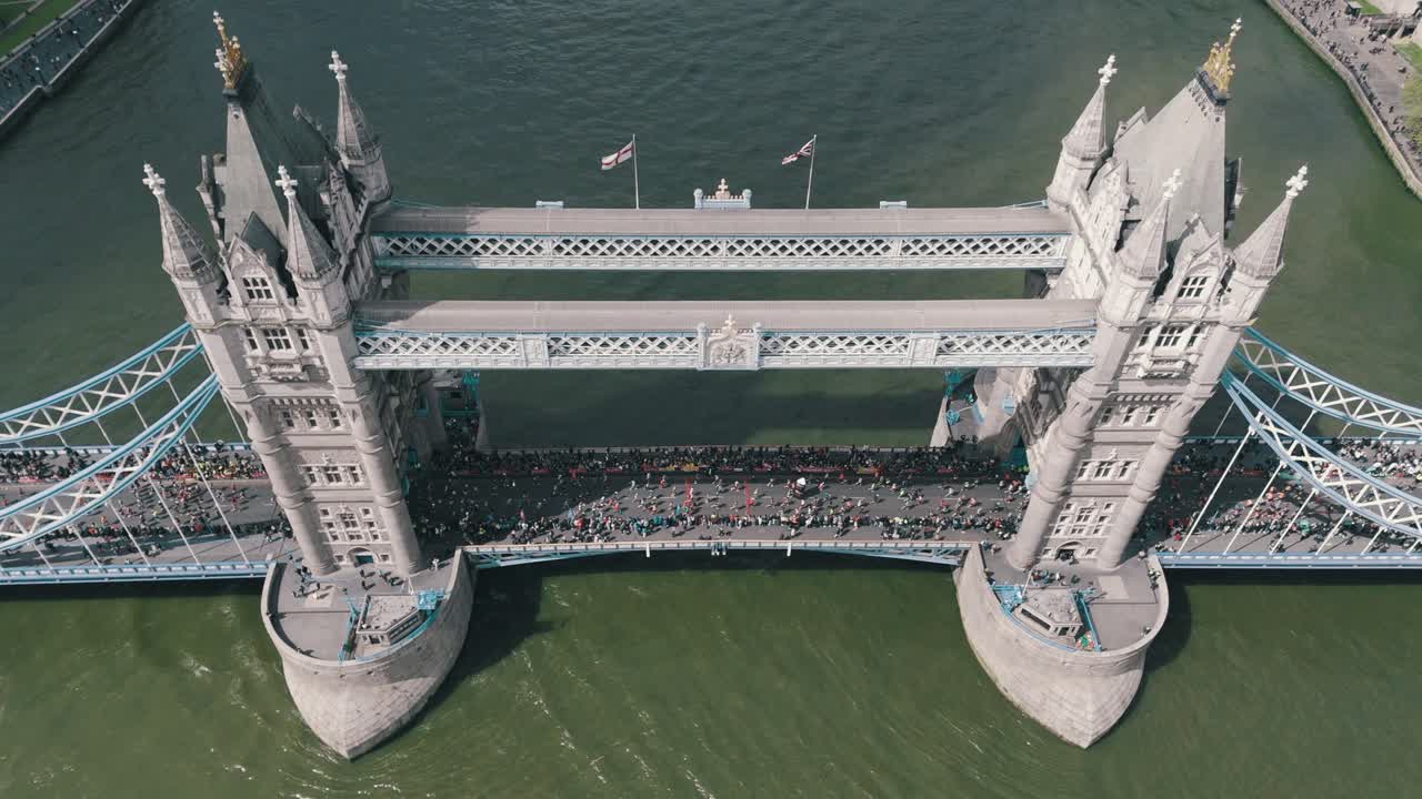 Runners race in London Marathon across Tower Bridge, River Thames, England, aerial static